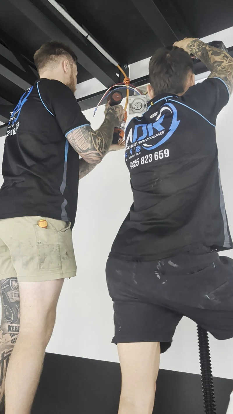 Two NDR team members working together on electrical wiring