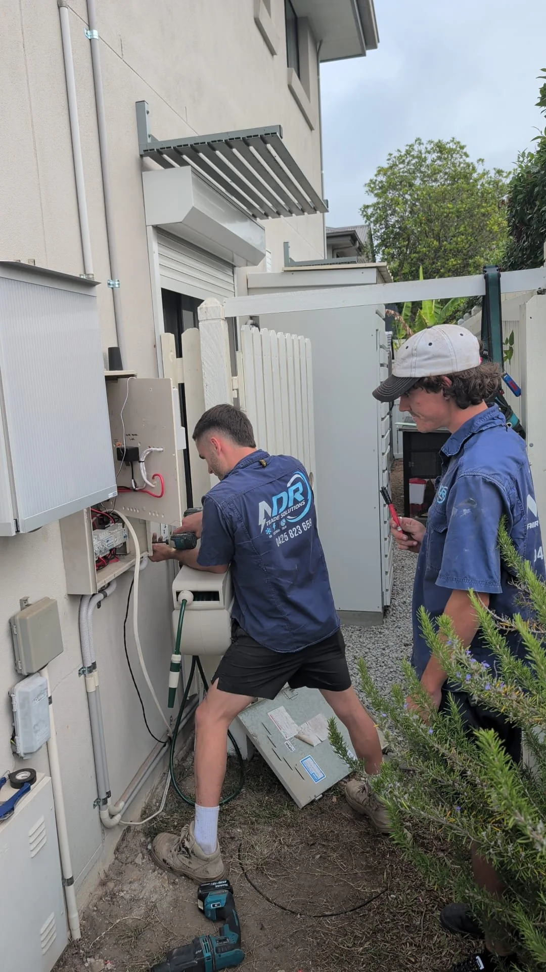 NDR team working on solar electrical equipment beside a home